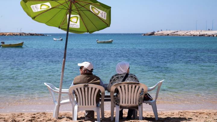 An elderly couple relax on Gleem Beach.